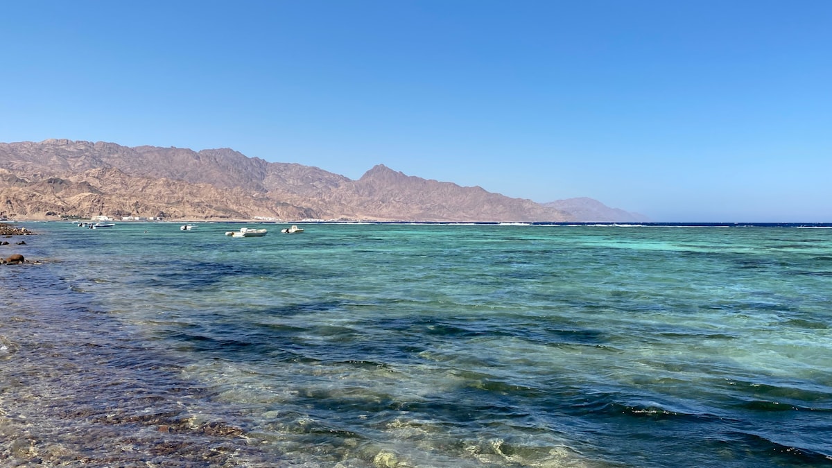 Crystal turquoise water of the Red Sea at Dahab with the arid Sinai mountains rising behind, Egypt