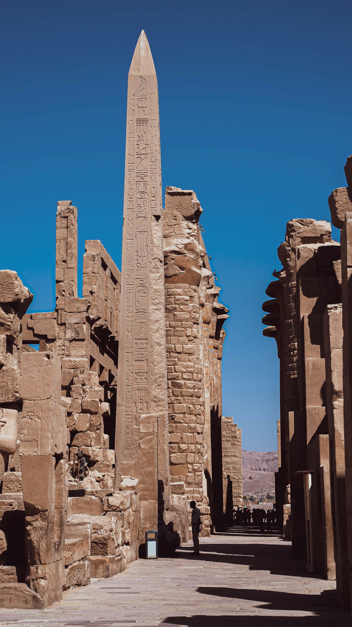 Obelisk covered in hieroglyphs rising above the stone ruins of Karnak Temple, Luxor, Egypt