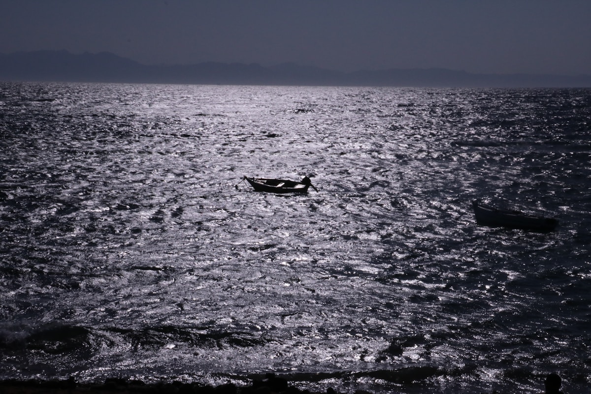 Small fishing boat on the moonlit Red Sea with Sinai mountains on the horizon, Dahab