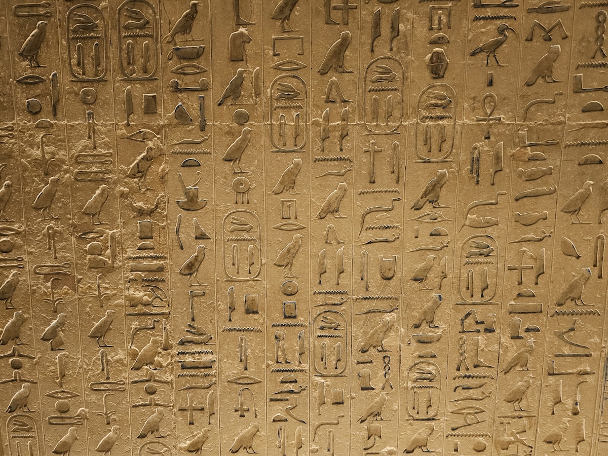 Rock-cut tomb at Tell el-Amarna with Amarna-style painted relief showing elongated figures under the Aten disc