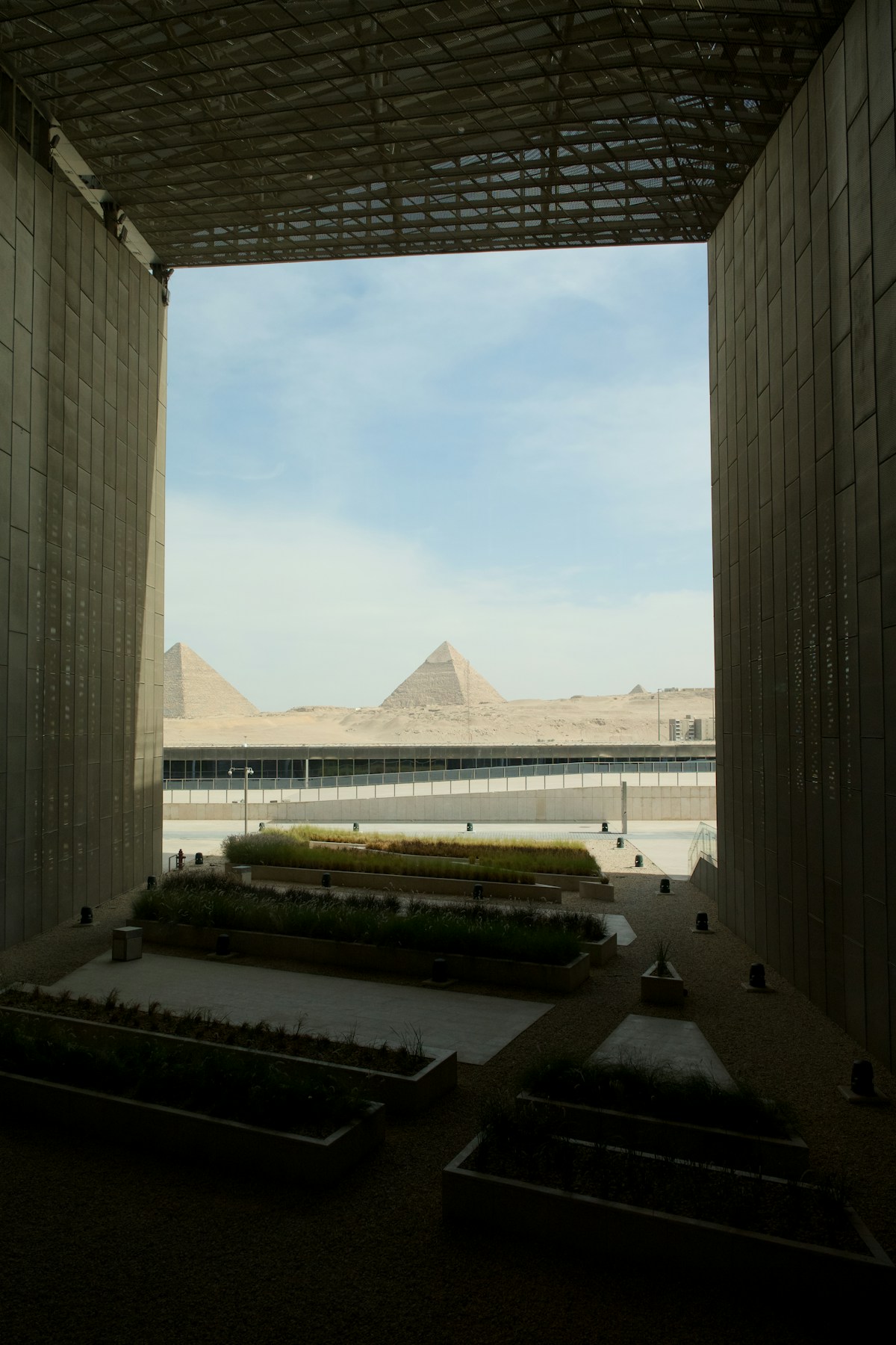 The Pyramids of Giza seen through the modern archway of the Grand Egyptian Museum