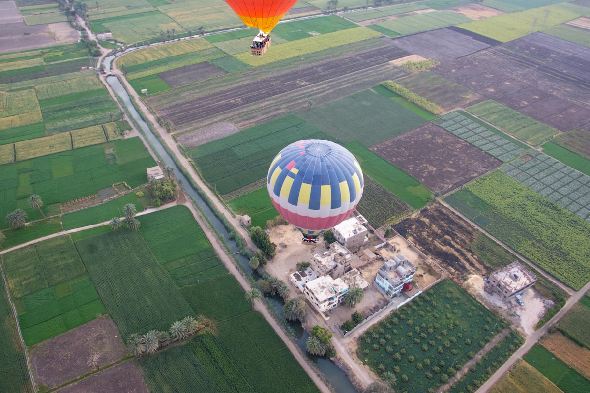 Hot air balloons drifting over the green Nile Valley fields near Luxor, Egypt