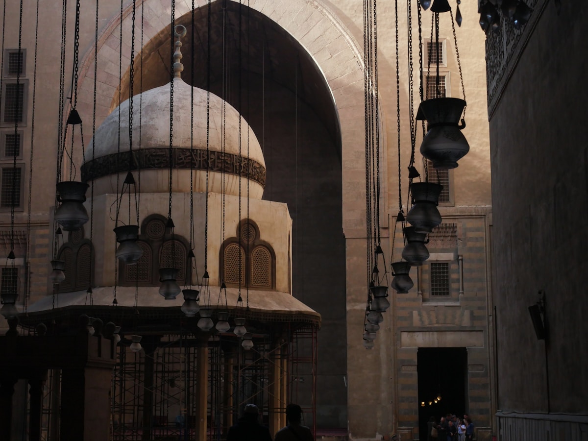 Ornate interior of the Sultan Hassan mosque in Cairo with hanging lanterns