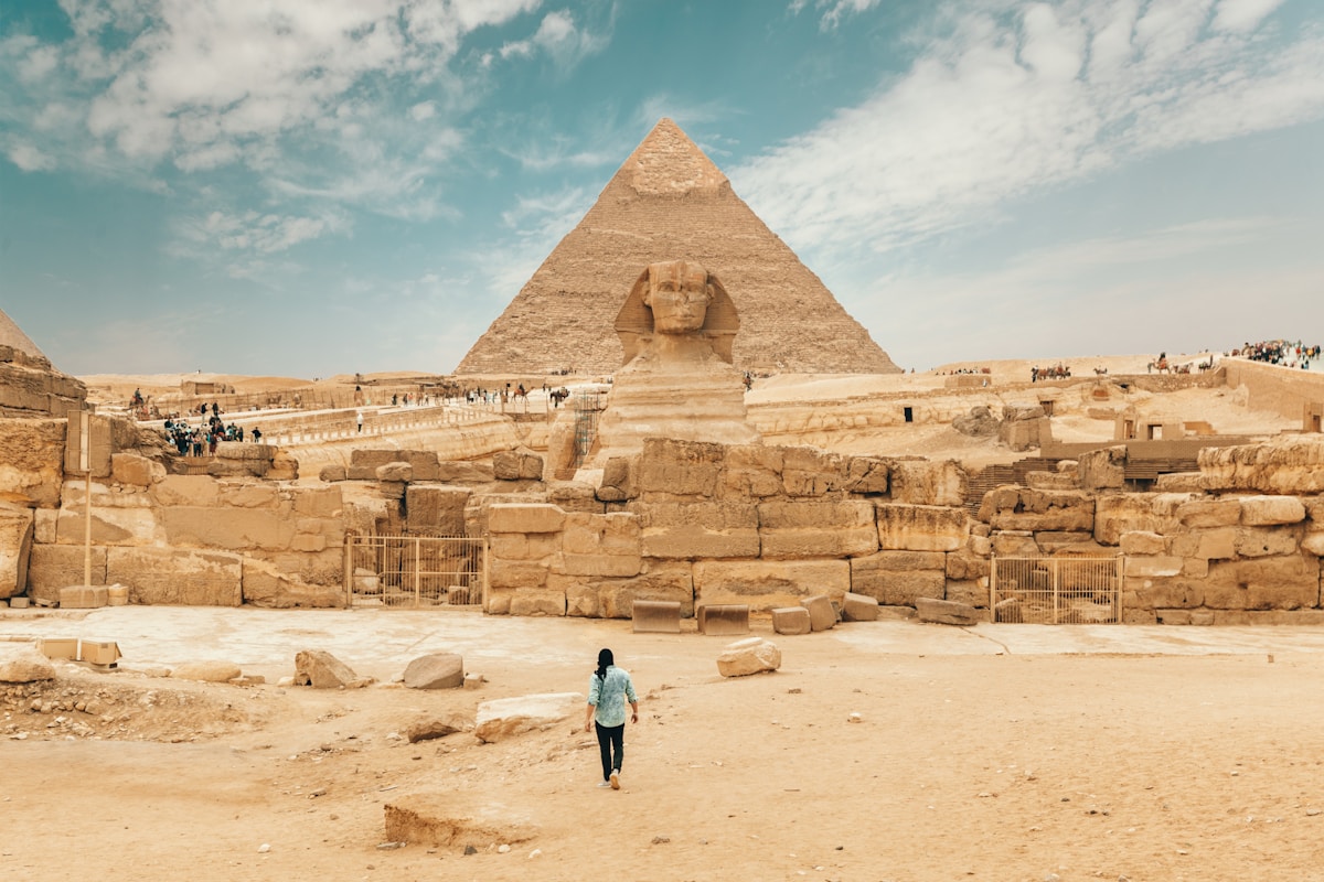 Person walking towards the Great Sphinx with the Pyramid of Khafre behind - the Giza Plateau is the main day trip destination from Sharm el-Sheikh