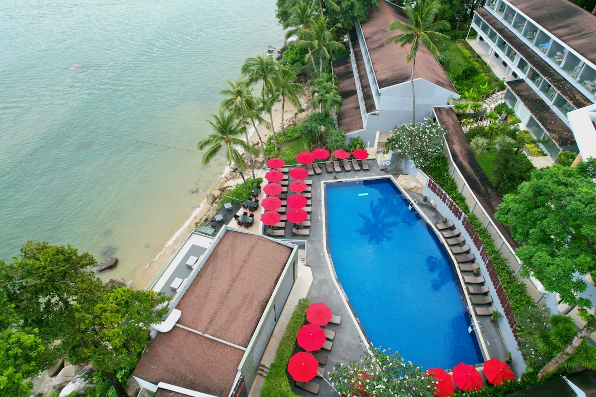 Aerial view of a waterfront resort with pool and red parasols, El Gouna