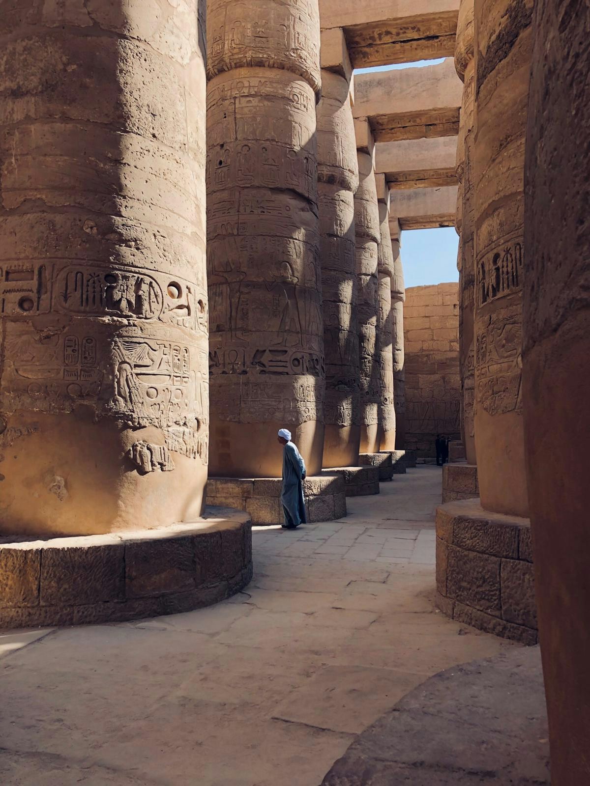 Homme marchant entre les colonnes hiéroglyphiques du temple de Karnak, Louxor, Égypte